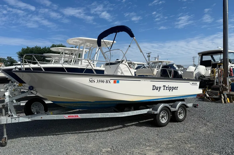 Slide: The Image of 2024 Boston Whaler 190 Montauk boat named "Day Tripper" on a trailer in a marina. - 9