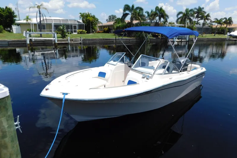 Slide: The Image of 2008 Grady-White Tournament 205 boat with blue canopy docked on calm water. - 0