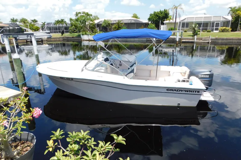 Slide: The Image of 2008 Grady-White Tournament 205 boat with blue canopy docked on calm water. - 2