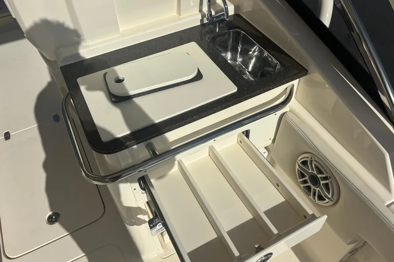 Slide: The Image of 2026 Scout 255 Dorado boat interior with sink, cutting board, and storage drawers. - 18