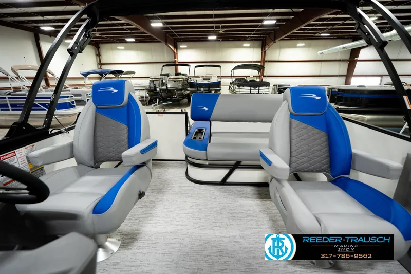 Slide: The Image of 2026 Bennington 21 SSB pontoon boat interior in showroom, featuring blue and white seating. - 16