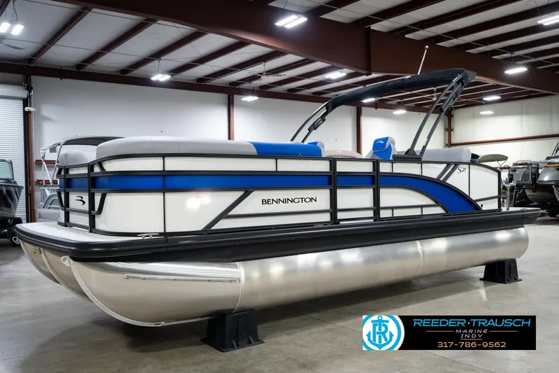 Slide: The Image of 2026 Bennington 21 SSB pontoon boat in showroom with blue accents and canopy. - 2