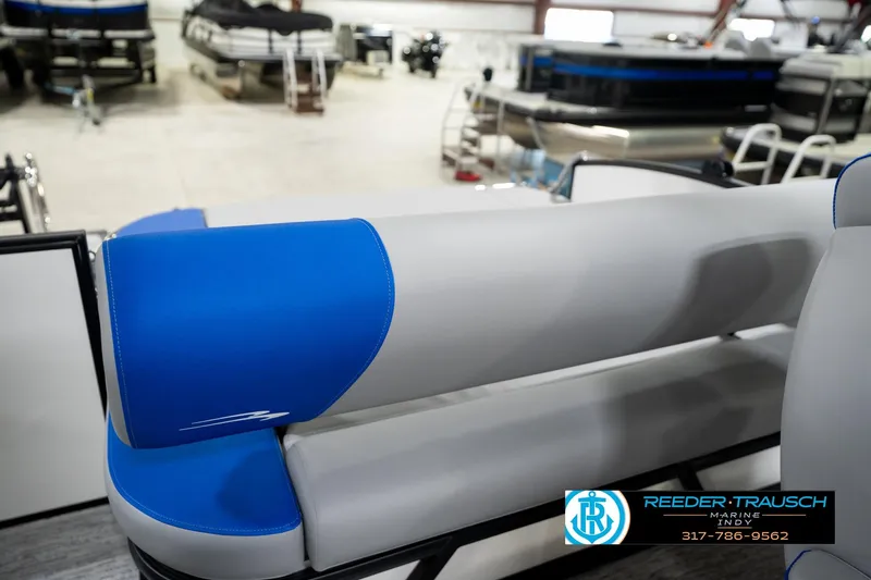 Slide: The Image of 2026 Bennington 21 SSB pontoon boat interior in showroom, featuring blue and gray seating. - 26