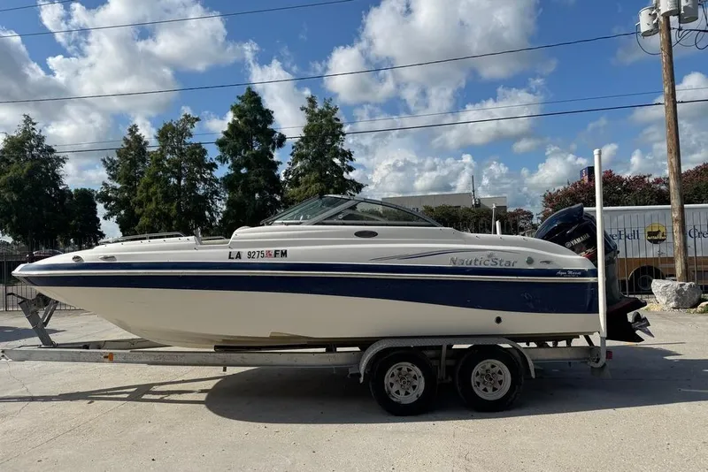 Slide: The Image of 2006 NauticStar 210 DC Sport Deck boat on trailer, parked outdoors under a blue sky. - 6
