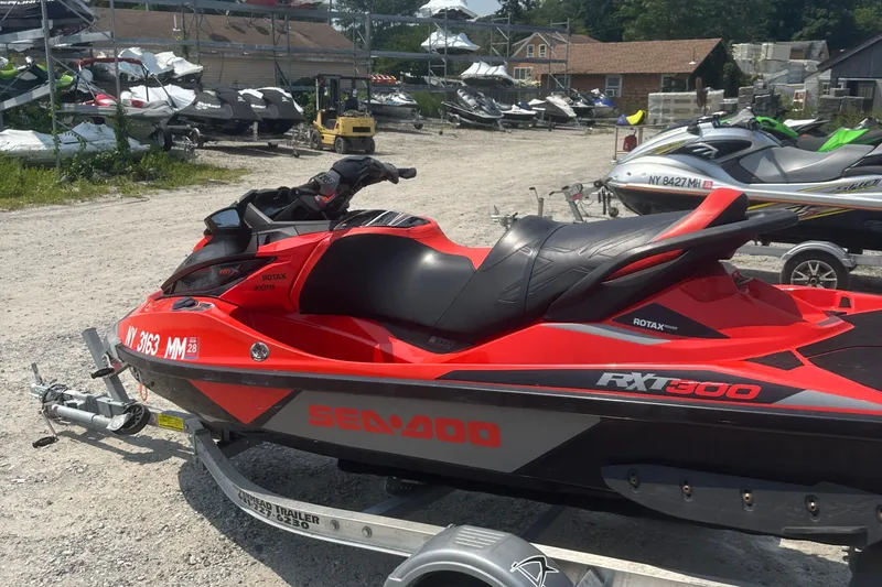 Slide: The Image of 2016 Sea-Doo RXT-X 300 jet ski in vibrant red, parked on a trailer. - 6