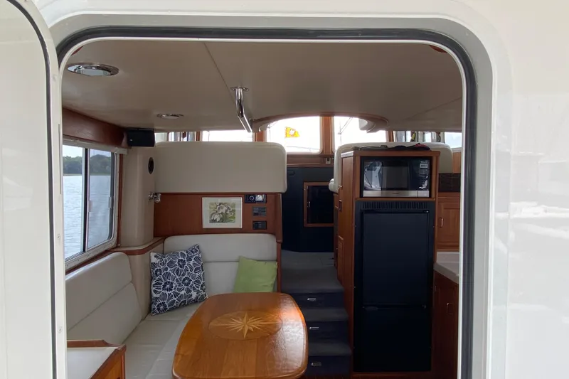 Slide: The Image of Interior of a 2003 American Tug 34, featuring a cozy dining area and kitchenette. - 22