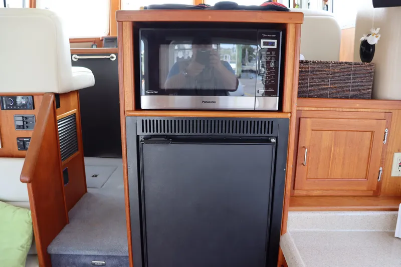 Slide: The Image of Interior of 2003 American Tug 34 featuring microwave and refrigerator in wooden cabinetry. - 32