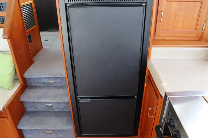 Slide: The Image of Interior of 2003 American Tug 34, featuring stairs and kitchen area with refrigerator. - 33