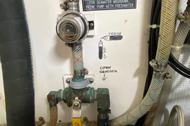 Slide: The Image of Seawater washdown system on a 2003 American Tug 34, featuring labeled valves and hoses. - 63