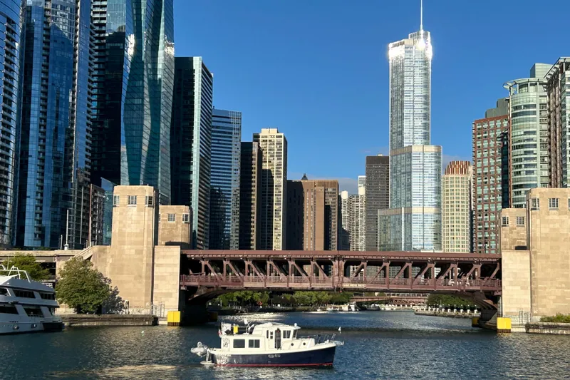 Slide: The Image of A 2003 American Tug 34 boat on a river with a city skyline backdrop. - 68