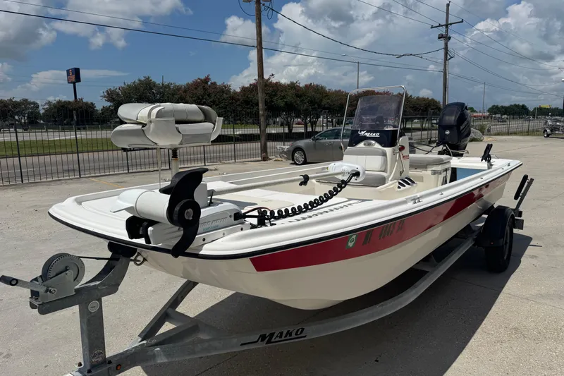 Slide: The Image of 2018 Mako Pro Skiff 17 CC boat on trailer, parked outdoors under a cloudy sky. - 8