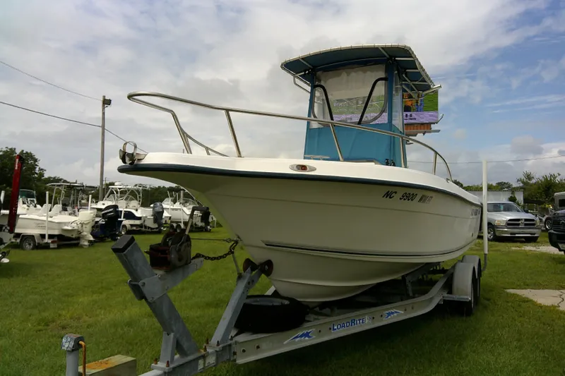 Slide: The Image of 2001 Key West boat on trailer in grassy lot, surrounded by other boats and vehicles. - 2