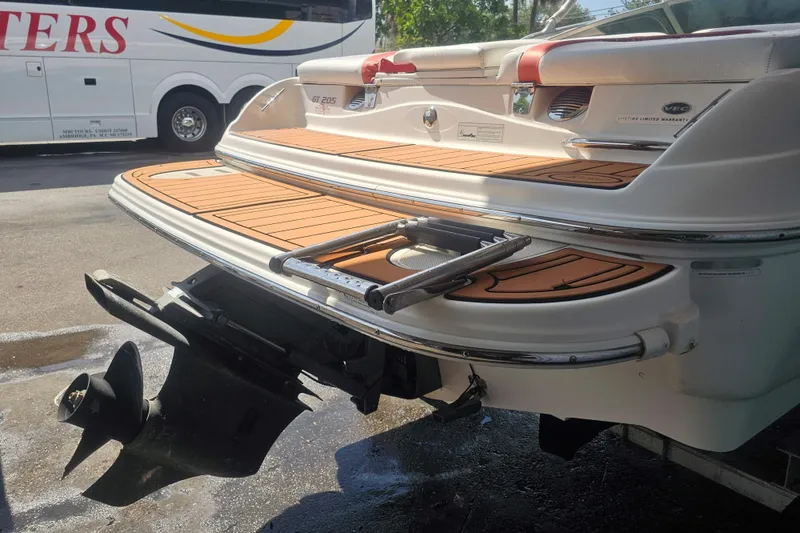 Slide: The Image of 2008 Glastron GT 205 boat stern with swim platform and ladder, parked near a bus. - 16