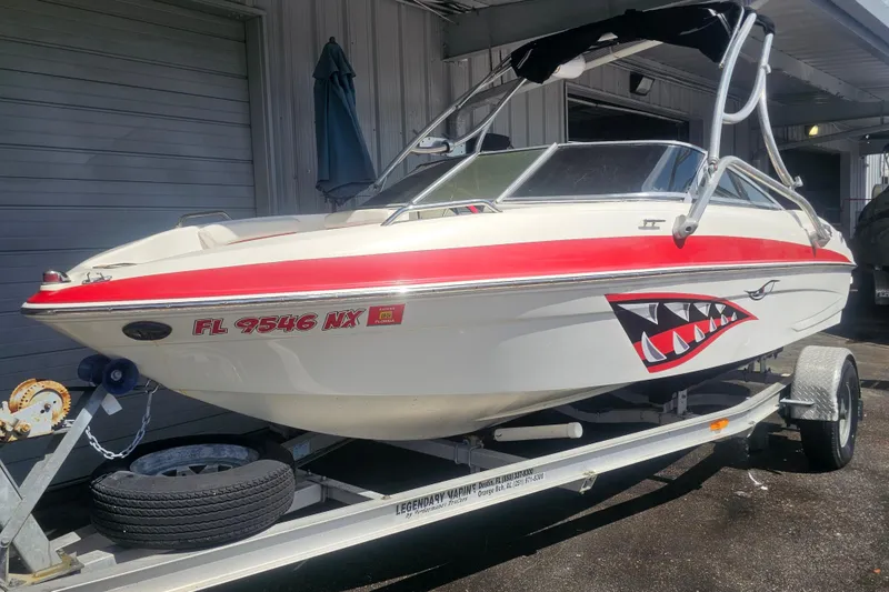 Slide: The Image of 2008 Glastron GT 205 boat with shark mouth decal on trailer, parked outdoors. - 2