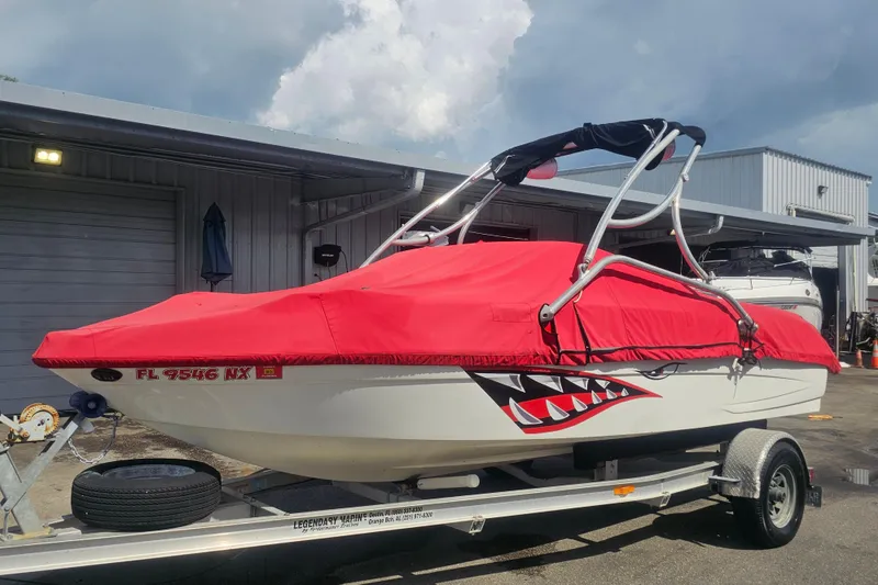 Slide: The Image of 2008 Glastron GT 205 boat with red cover on trailer, shark decal visible. - 3