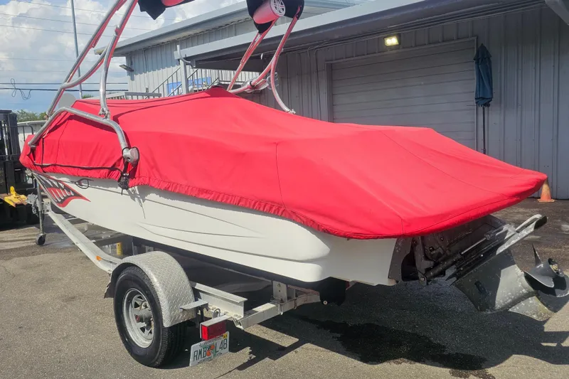 Slide: The Image of 2008 Glastron GT 205 boat with red cover on trailer, parked outside a building. - 4