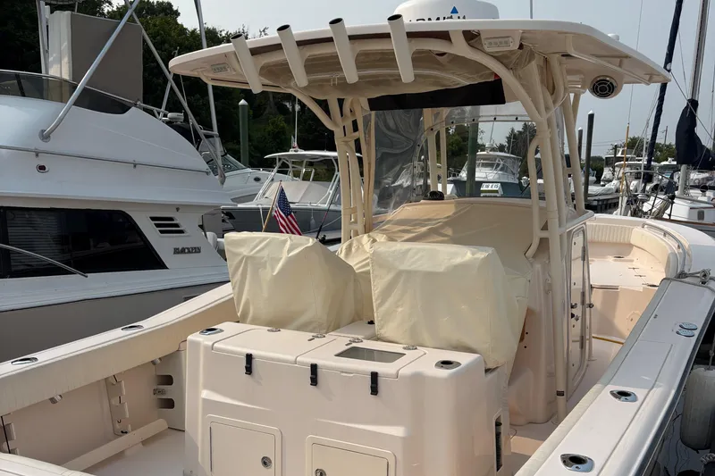 Slide: The Image of 2013 Grady-White Canyon 306 boat docked, featuring covered seating and American flag. - 14
