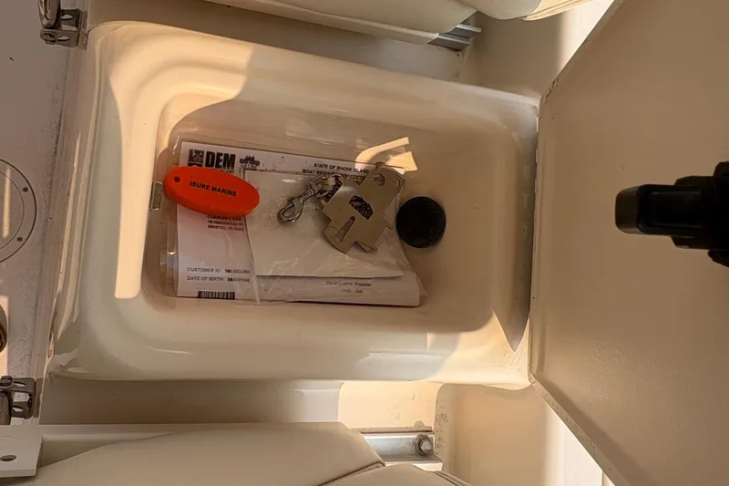Slide: The Image of Open storage compartment on 2013 Grady-White Canyon 306 boat with keys and documents. - 37
