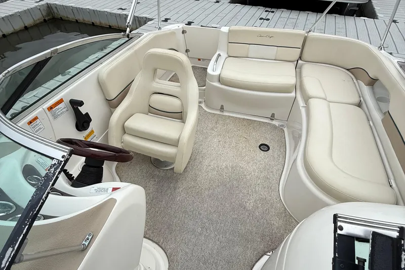 Slide: The Image of Interior of a 2000 Chris-Craft 230 Deck Boat with beige seating and steering wheel. - 6