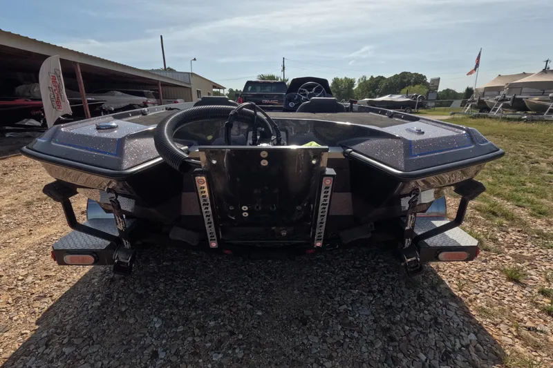 Slide: The Image of 2021 Bullet 21XRS boat rear view on gravel lot, showcasing sleek design and trailer setup. - 11
