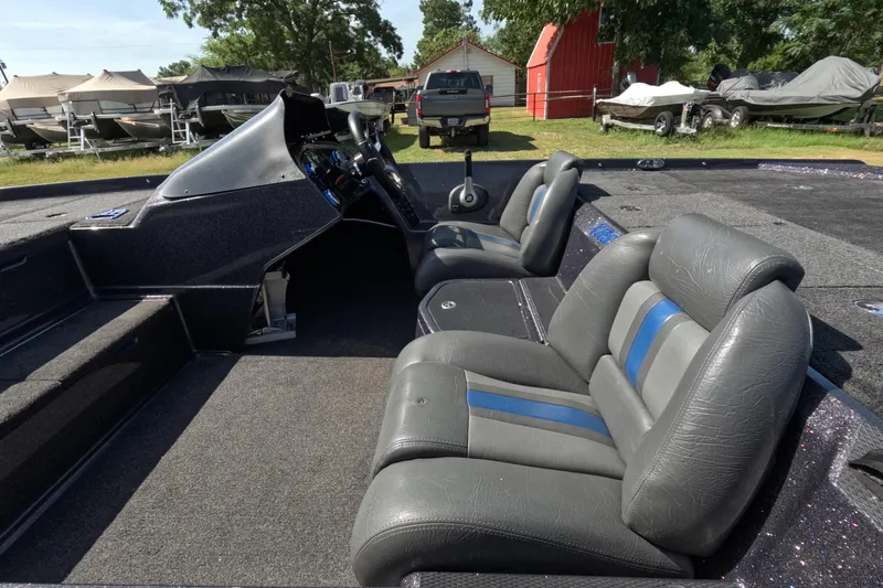 Slide: The Image of 2021 Bullet 21XRS boat interior with gray and blue seats, parked outdoors. - 5