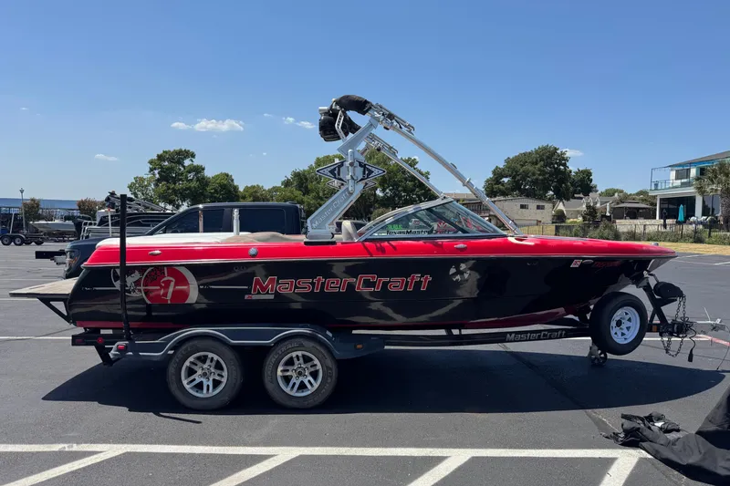 Slide: The Image of 2008 MasterCraft X1 boat on trailer, red and black design, parked outdoors. - 1