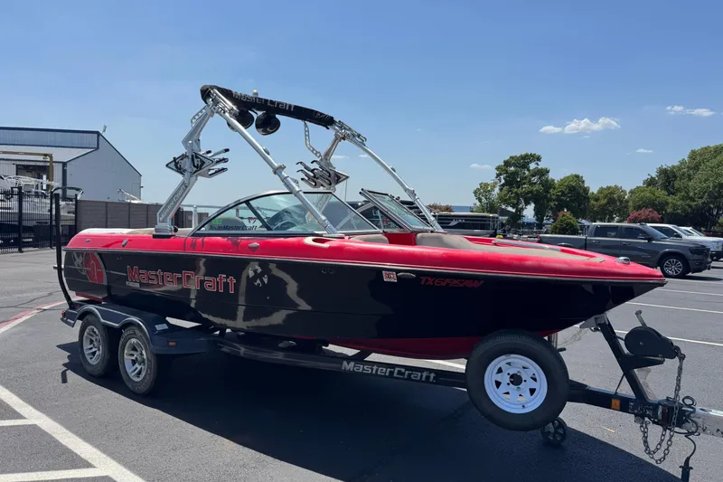 Slide: The Image of 2008 MasterCraft X1 boat on trailer, red and black design, parked outdoors. - 2