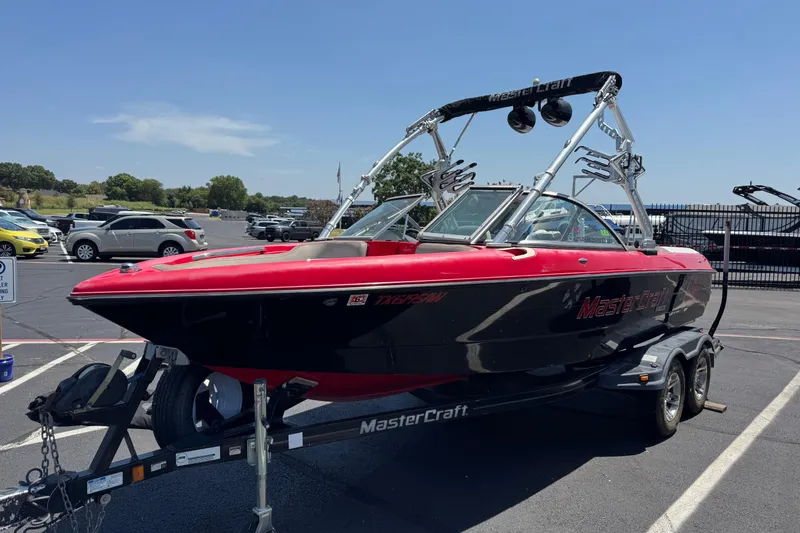 Slide: The Image of 2008 MasterCraft X1 boat with red and black design on a trailer in a parking lot. - 3