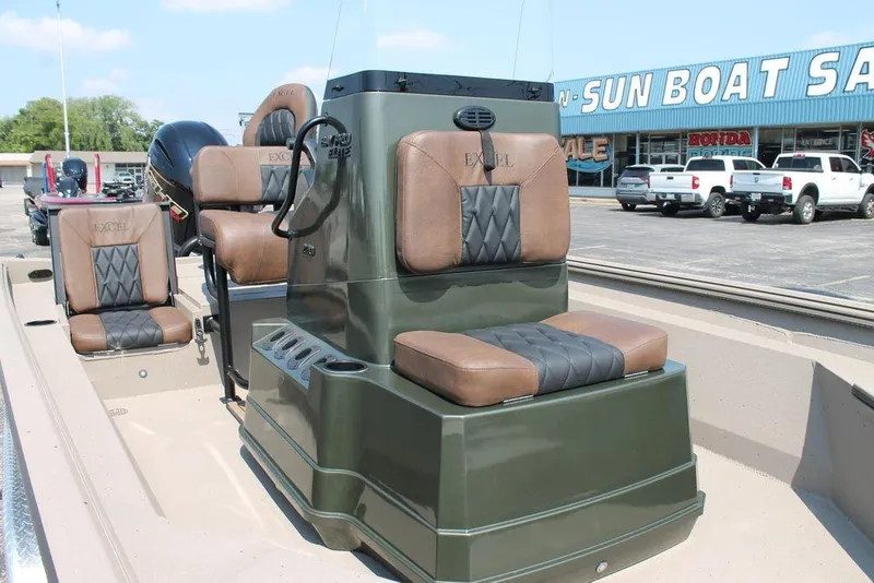 Slide: The Image of 2026 Excel Bay Pro Elite 220 boat with brown and black seating, displayed at a dealership. - 7