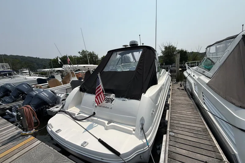 Slide: The Image of 2003 Sea Ray 340 Sundancer docked, featuring a black cover and American flag. - 2