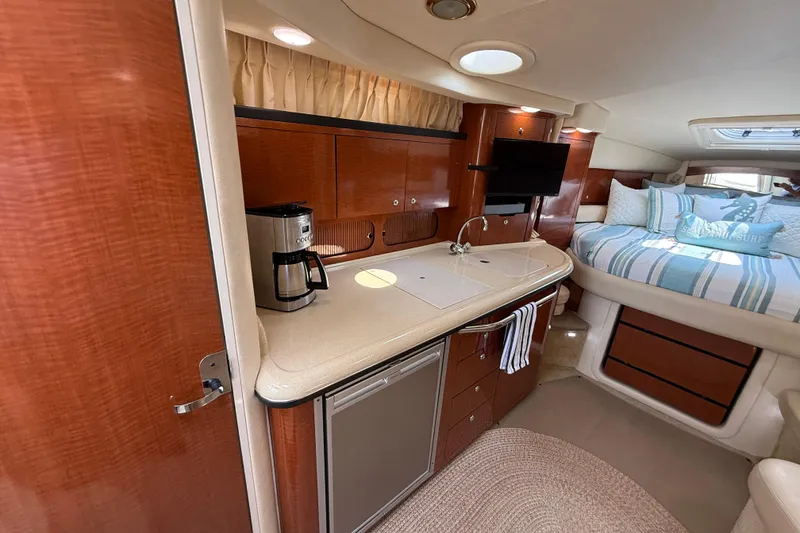 Slide: The Image of 2003 Sea Ray 340 Sundancer interior with kitchenette, bed, and cozy seating area. - 35