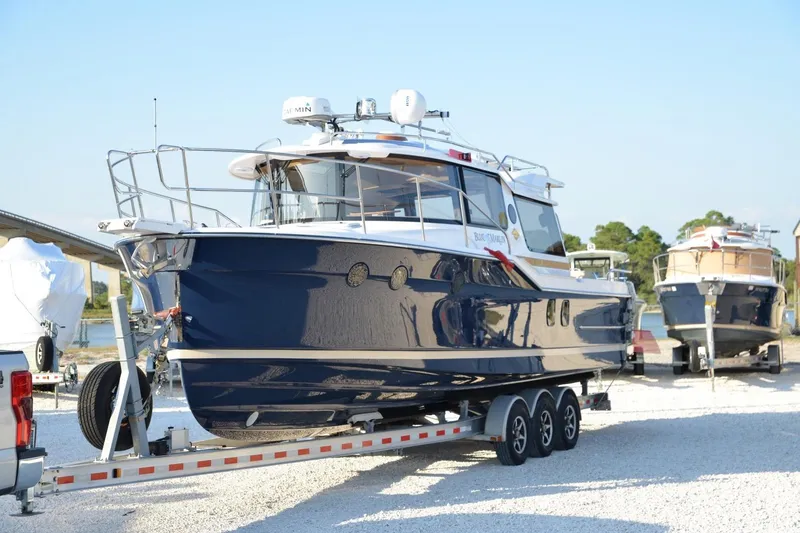 Slide: The Image of 2026 Ranger Tugs R-29 S boat on a trailer, parked outdoors. - 7