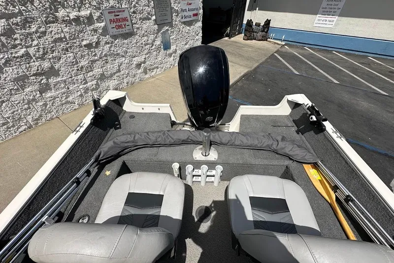 Slide: The Image of 2019 Tracker Pro Guide V-16 WT boat interior with seats and motor, parked outside. - 11