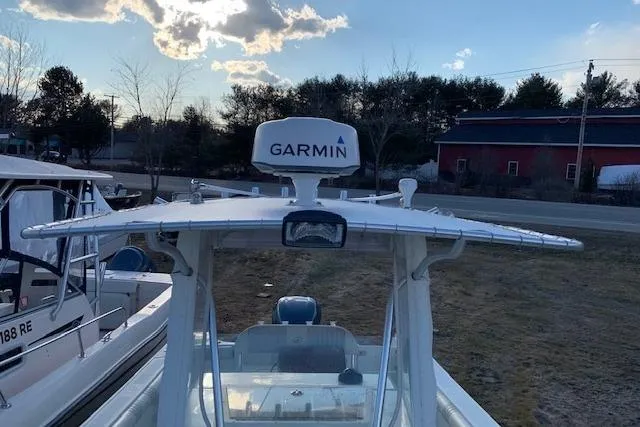 Slide: The Image of 2009 Sailfish 2360 CC boat with Garmin radar, parked outdoors under a cloudy sky. - 2