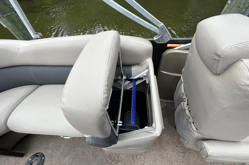 Slide: The Image of Premier 250 S-Series 2010 boat seat with storage compartment open, near water. - 15