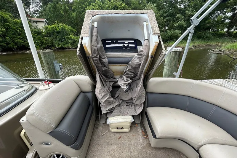 Slide: The Image of 2010 Premier 250 S-Series boat interior with seating and storage compartment, docked by a river. - 18