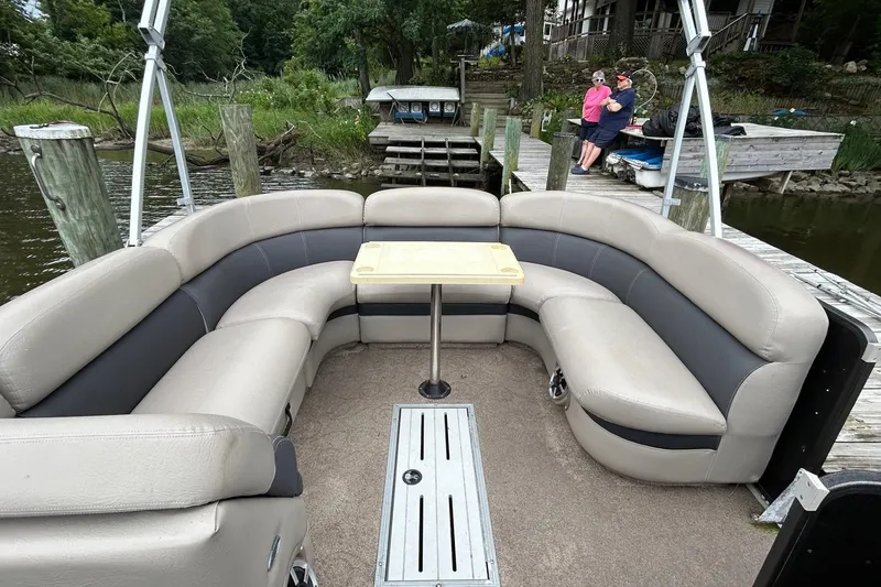 Slide: The Image of 2010 Premier 250 S-Series pontoon boat with beige seating and table, docked by a lake. - 22