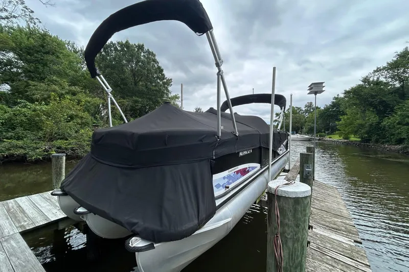 Slide: The Image of 2010 Premier 250 S-Series pontoon boat docked with cover, surrounded by trees and water. - 28
