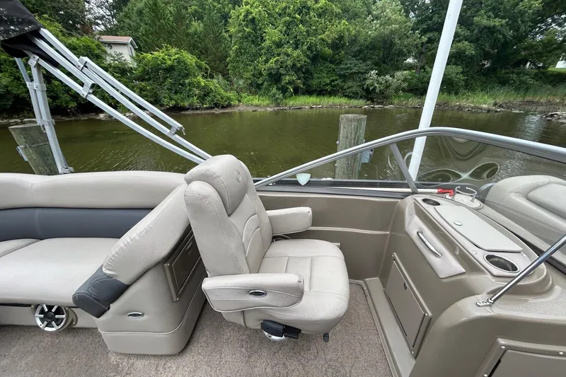 Slide: The Image of Premier 250 S-Series 2010 boat interior with beige seating and console, near a lush riverside. - 6