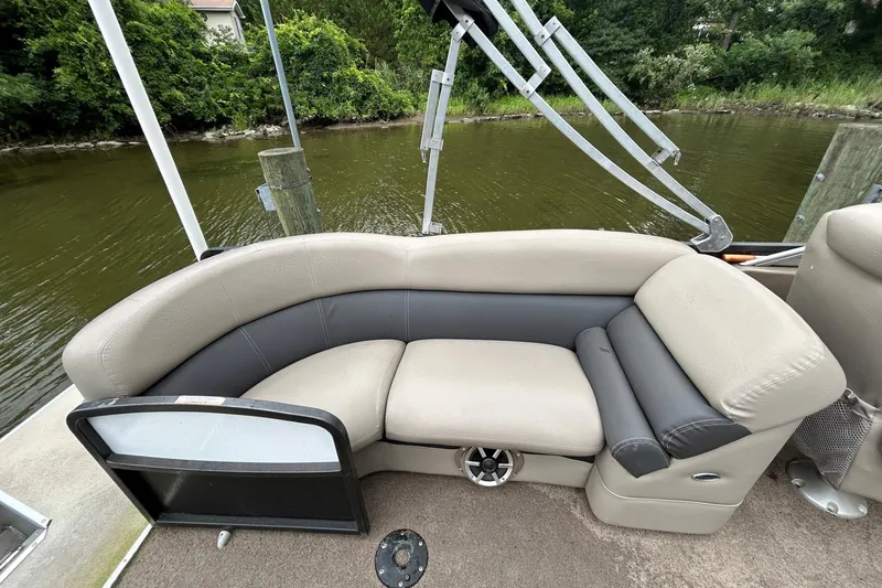 Slide: The Image of Premier 250 S-Series 2010 pontoon boat seating with beige and gray upholstery by the water. - 7