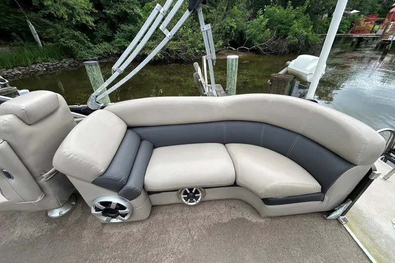 Slide: The Image of Premier 250 S-Series 2010 boat seating with beige and gray upholstery, docked by a lush shoreline. - 9