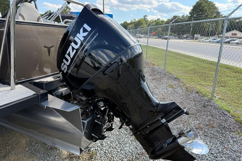 Slide: The Image of 2025 Tahoe Pontoon Sport 85 Rear Fish with Suzuki outboard motor, parked on gravel. - 10