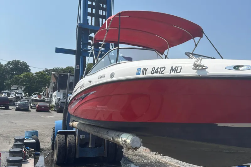 Slide: The Image of 2007 Yamaha Boats SX210 with red canopy on a lift at a marina. - 2