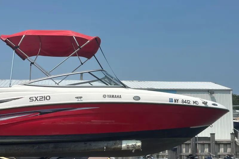 Slide: The Image of 2007 Yamaha SX210 boat with red canopy, docked near a building. - 5