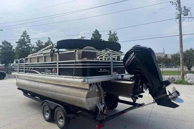 Slide: The Image of 2021 Sun Tracker Fishin' Barge 20 DLX pontoon boat on trailer, featuring Mercury outboard motor. - 7