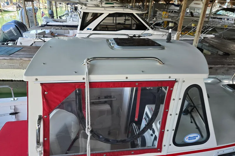 Slide: The Image of 2013 Atlas Boat Works Pompano 21 docked, featuring red trim and a sleek cabin design. - 11