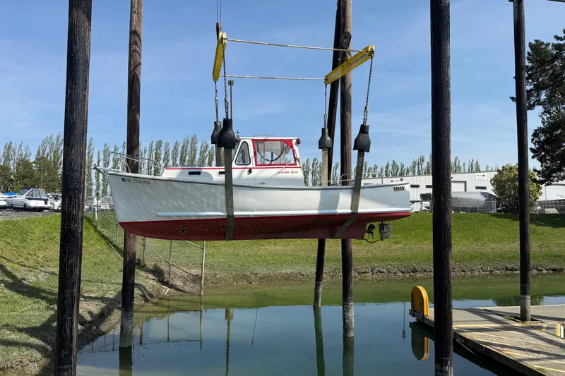 Slide: The Image of 2013 Atlas Boat Works Pompano 21 suspended over water by a lift. - 4