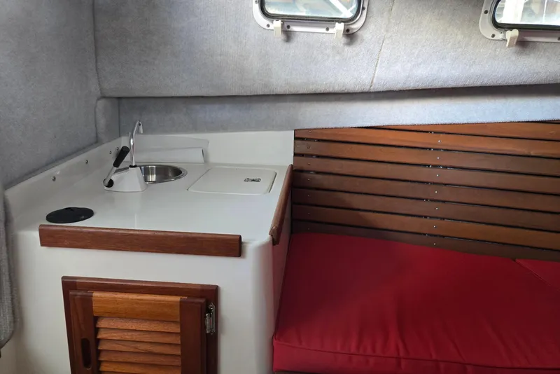 Slide: The Image of 2013 Atlas Boat Works Pompano 21 interior with sink, wooden cabinetry, and red cushioned seating. - 45