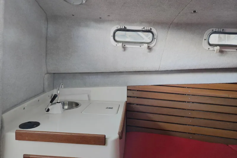Slide: The Image of Interior of 2013 Atlas Boat Works Pompano 21, featuring compact kitchenette and wooden accents. - 46
