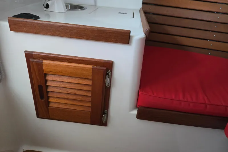 Slide: The Image of Interior of 2013 Atlas Boat Works Pompano 21, featuring wooden cabinet and red cushioned seat. - 47